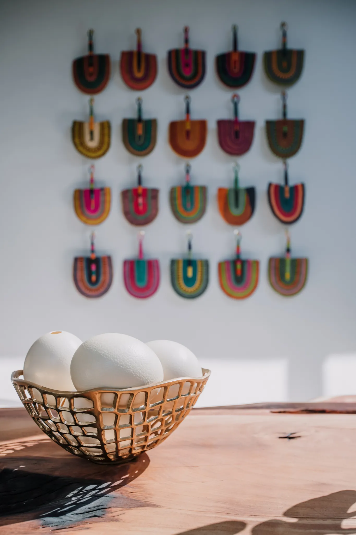 A bowl of ostrich egg decorations on a table and African decorations hanging on the wall.