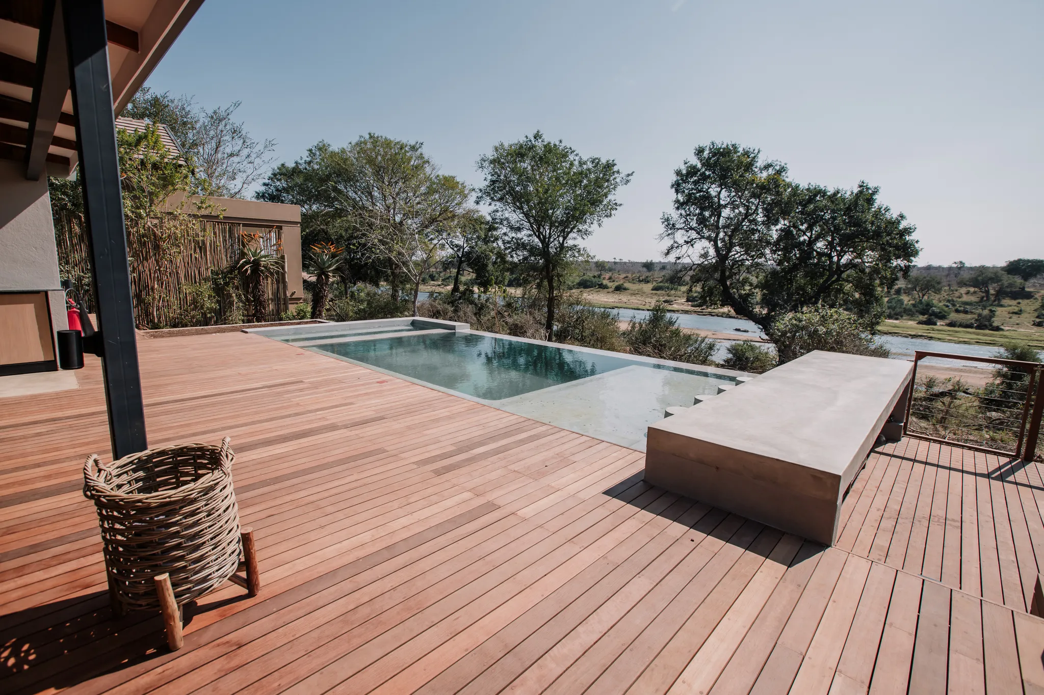 A pool area with a wooden deck and view of the surrounding nature.