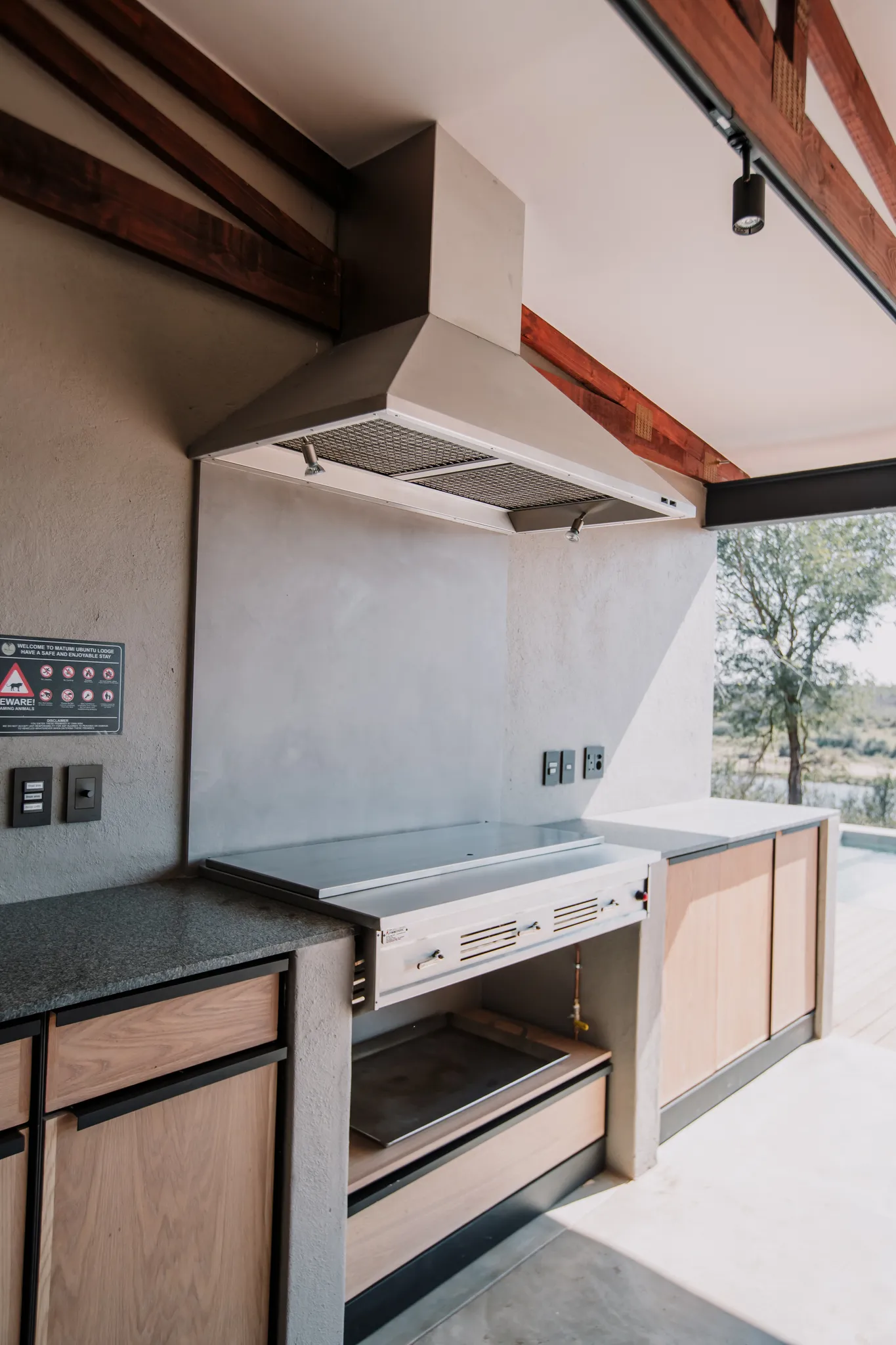 An outdoor kitchen with a braai and stove hood.