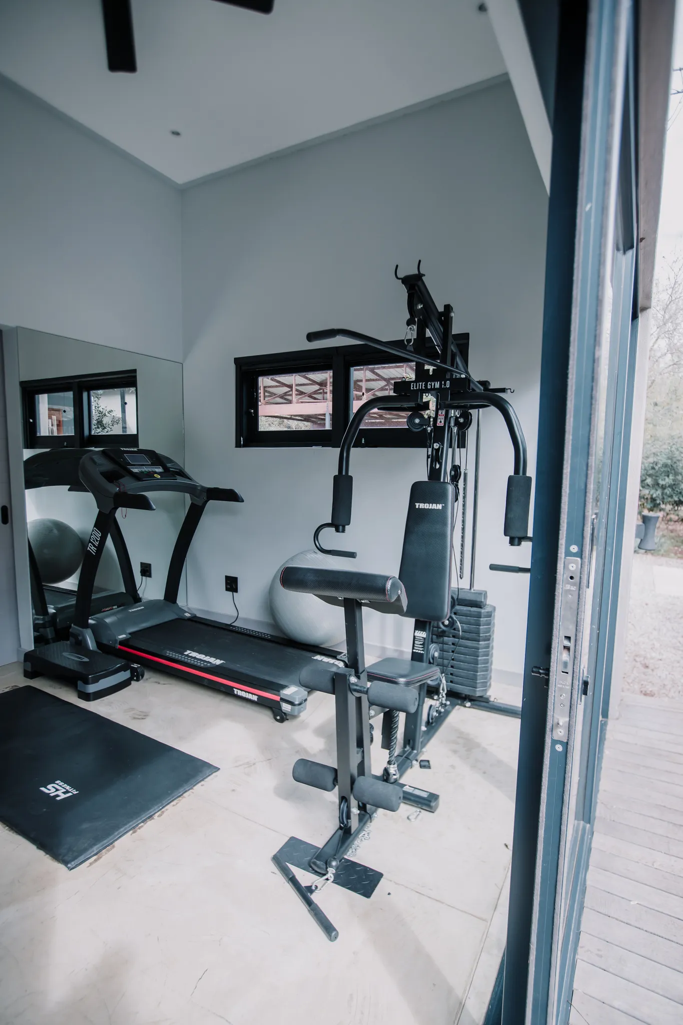 A home gym area with mutliple exercise machines.